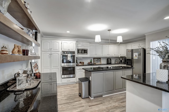 kitchen featuring white cabinetry, hanging light fixtures, ornamental molding, appliances with stainless steel finishes, and dark stone counters