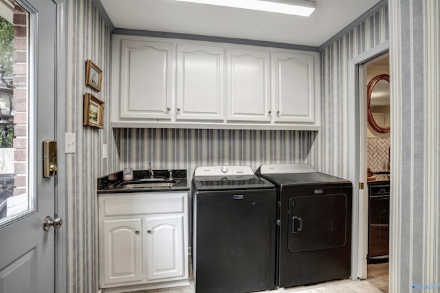 washroom with cabinets, washing machine and dryer, sink, and a healthy amount of sunlight