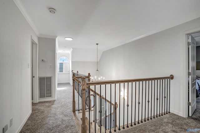 hall featuring carpet floors, ornamental molding, vaulted ceiling, and a notable chandelier