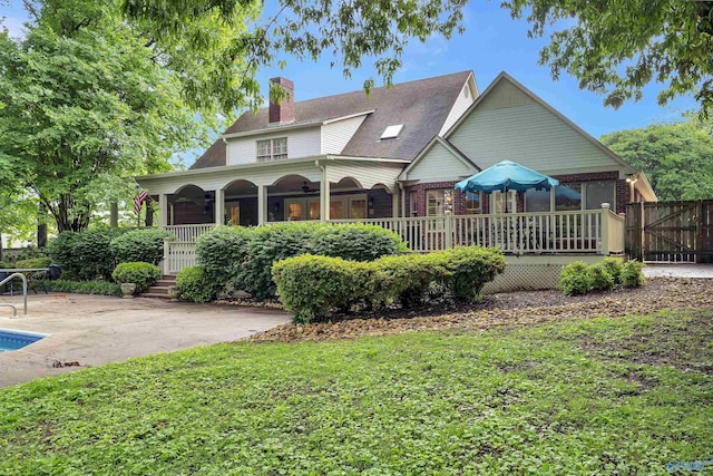 rear view of house featuring a wooden deck, a lawn, ceiling fan, and a patio area