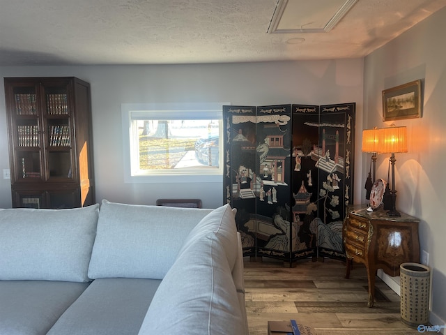 living room featuring attic access, a textured ceiling, and wood finished floors