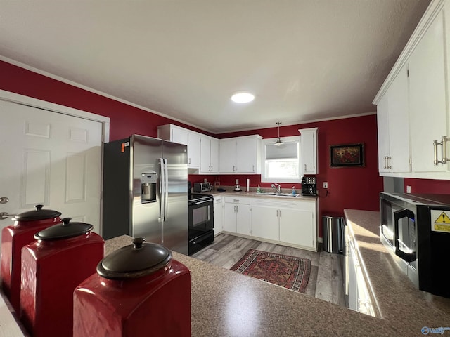 kitchen featuring crown molding, black range with electric stovetop, white cabinets, a sink, and stainless steel fridge