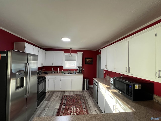 kitchen with crown molding, light wood-style flooring, appliances with stainless steel finishes, white cabinetry, and a sink