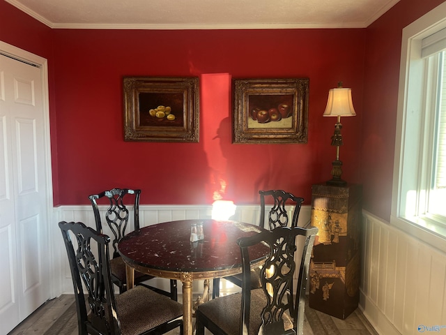 dining space with crown molding, wainscoting, plenty of natural light, and wood finished floors