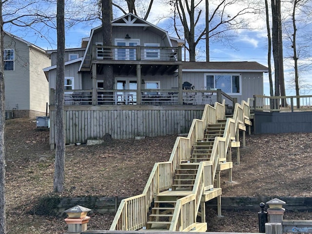 rear view of property with a balcony, stairway, and a wooden deck