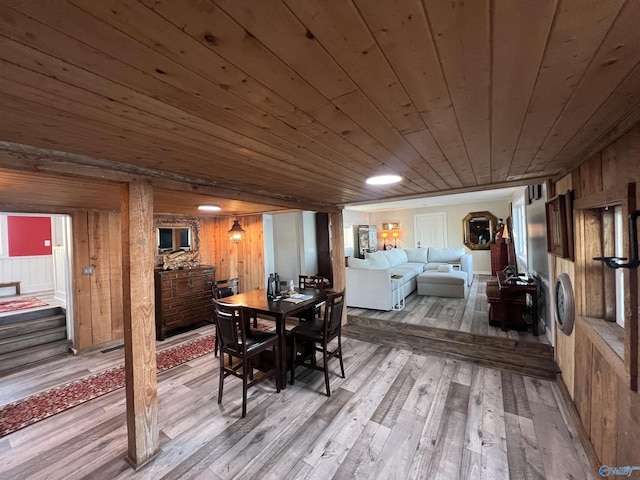 dining space featuring light wood-type flooring, wood walls, and wood ceiling