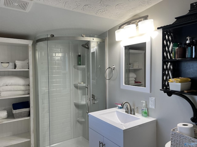 bathroom with a stall shower, visible vents, a textured ceiling, and vanity