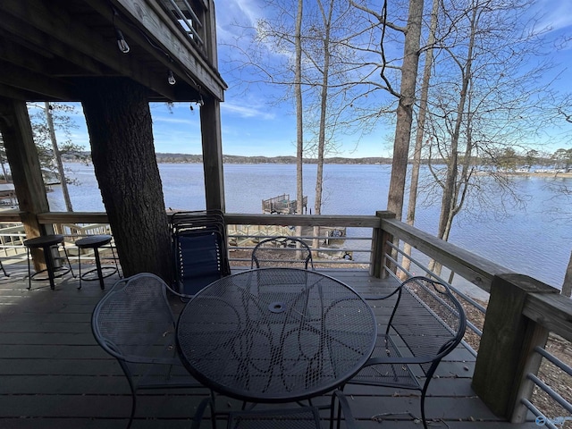 wooden terrace with outdoor dining space and a water view