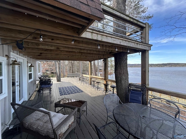 deck featuring outdoor dining area, a water view, and an outdoor bar