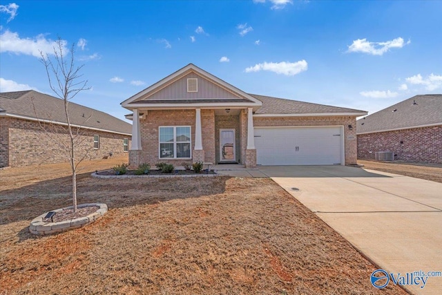 view of front of property featuring a garage, brick siding, driveway, and central AC unit