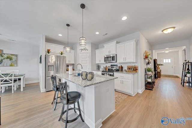 16604 Demi Dr, Athens, AL 35613 - kitchen featuring light wood finished floors, appliances with stainless steel finishes, a kitchen island with sink, white cabinets, and a kitchen bar