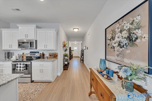 16604 Demi Dr, Athens, AL 35613 - kitchen featuring appliances with stainless steel finishes, light wood-type flooring, white cabinetry, and decorative backsplash