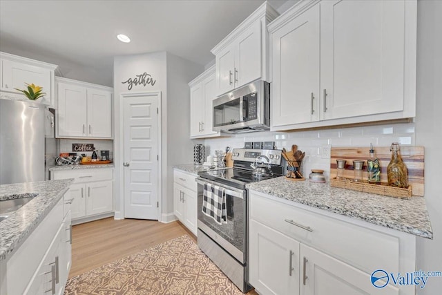 16604 Demi Dr, Athens, AL 35613 - kitchen featuring light stone counters, stainless steel appliances, light wood-type flooring, white cabinetry, and backsplash