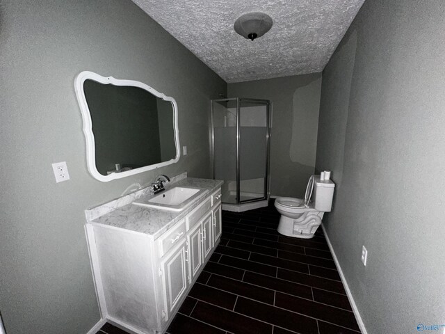 bathroom featuring walk in shower, a textured ceiling, toilet, vanity, and tile patterned floors