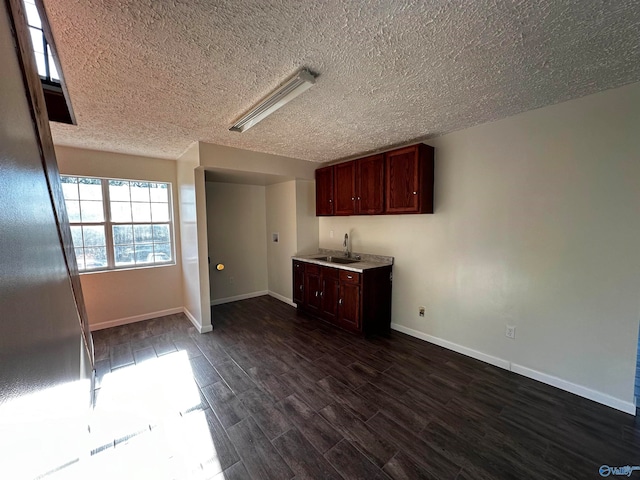 unfurnished living room featuring dark hardwood / wood-style floors, sink, and a textured ceiling