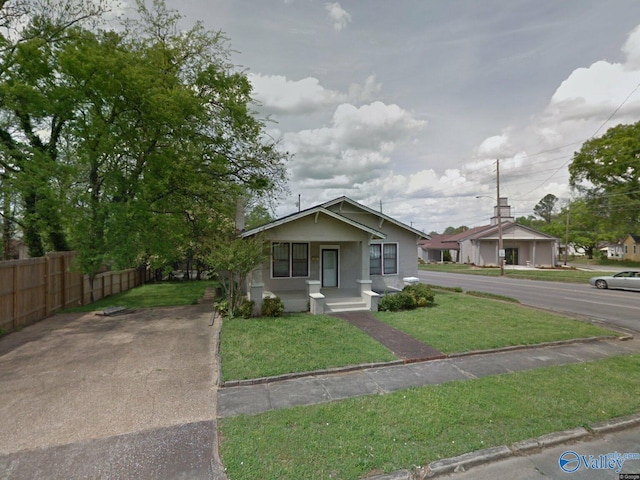 bungalow with a front yard, fence, and stucco siding