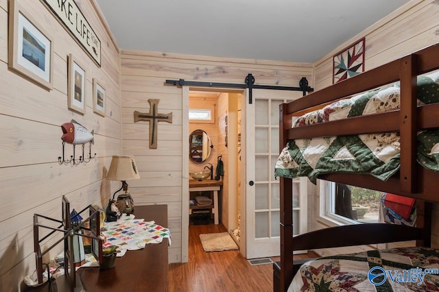 bedroom featuring a barn door, wood walls, and hardwood / wood-style flooring