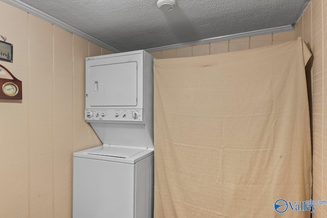 laundry room with a textured ceiling, crown molding, and stacked washer and clothes dryer