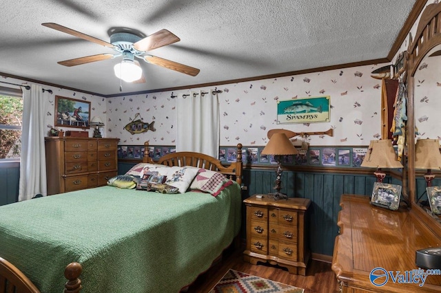 bedroom featuring ceiling fan, wood-type flooring, a textured ceiling, and ornamental molding