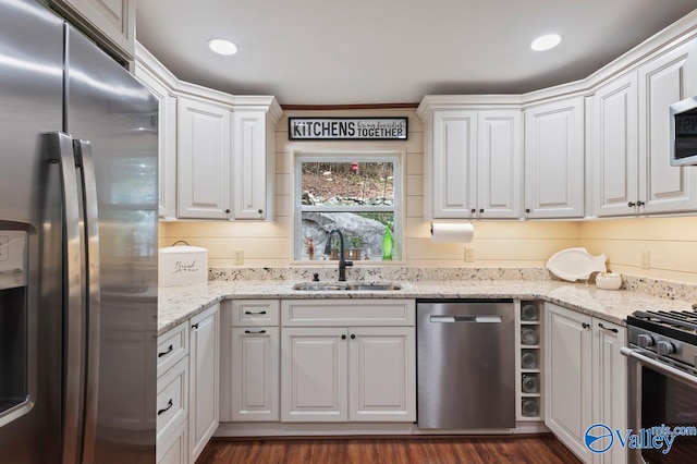 kitchen with appliances with stainless steel finishes, white cabinetry, dark wood-type flooring, and sink