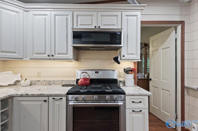 kitchen featuring white cabinets, appliances with stainless steel finishes, dark hardwood / wood-style floors, and light stone countertops