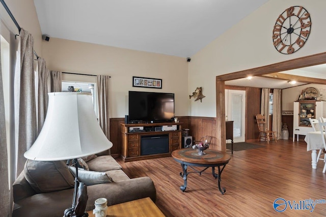 living room with hardwood / wood-style flooring, lofted ceiling, and wood walls