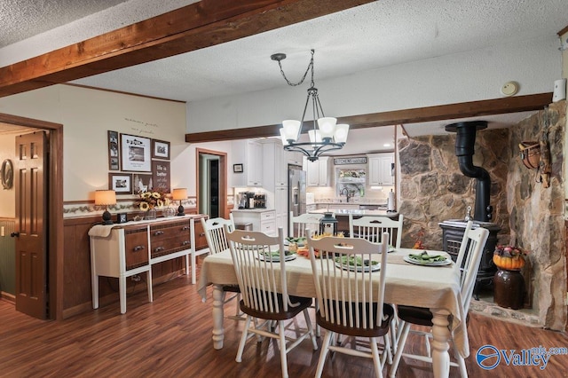 dining room featuring a wood stove, an inviting chandelier, sink, a textured ceiling, and dark hardwood / wood-style flooring