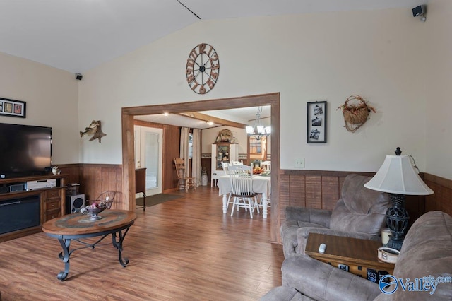 living room with a wealth of natural light, hardwood / wood-style flooring, a chandelier, lofted ceiling, and wood walls