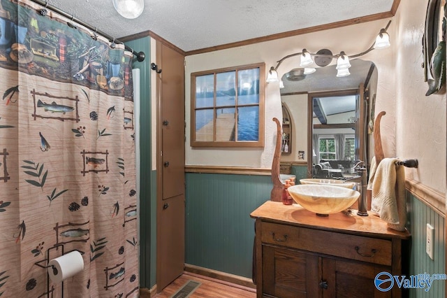 bathroom featuring vanity, crown molding, hardwood / wood-style flooring, a shower with shower curtain, and a textured ceiling