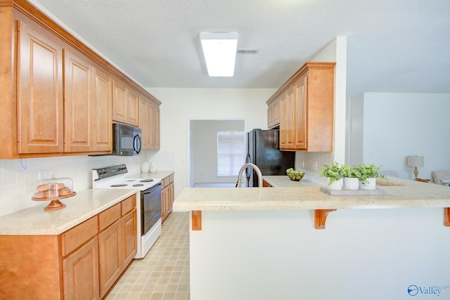 kitchen with tasteful backsplash, kitchen peninsula, a kitchen breakfast bar, and black appliances