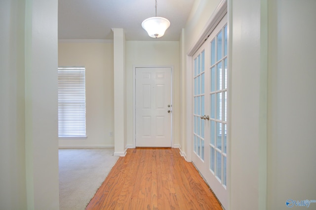 entryway with crown molding, light carpet, and french doors