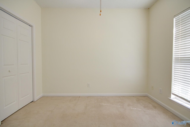 unfurnished bedroom with light carpet and a closet