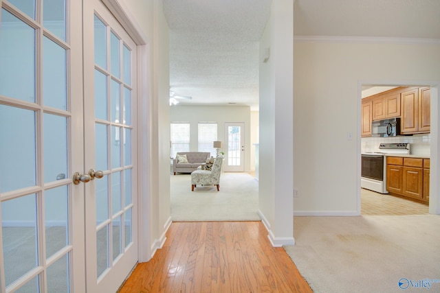 corridor with crown molding, light carpet, and french doors