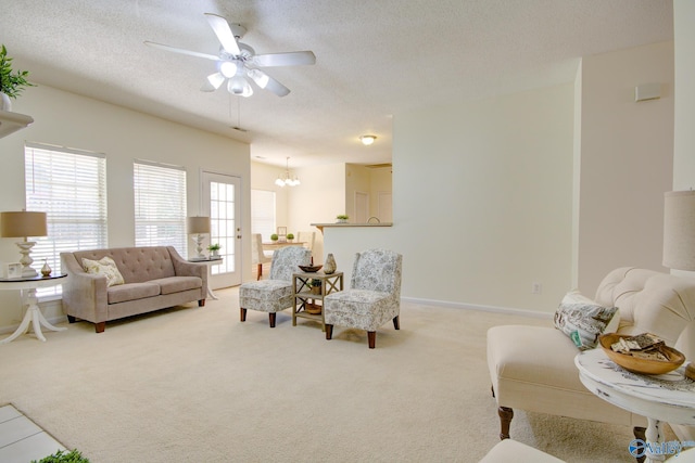 living room featuring carpet floors, ceiling fan with notable chandelier, and a textured ceiling