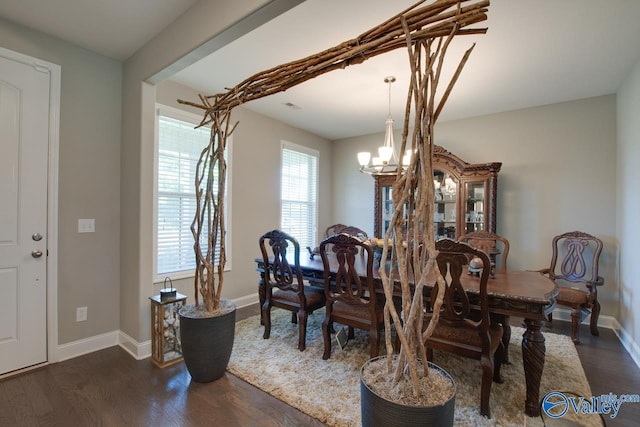 dining area with dark wood-type flooring and a notable chandelier