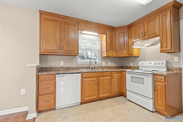 kitchen featuring under cabinet range hood, white appliances, a sink, baseboards, and brown cabinetry