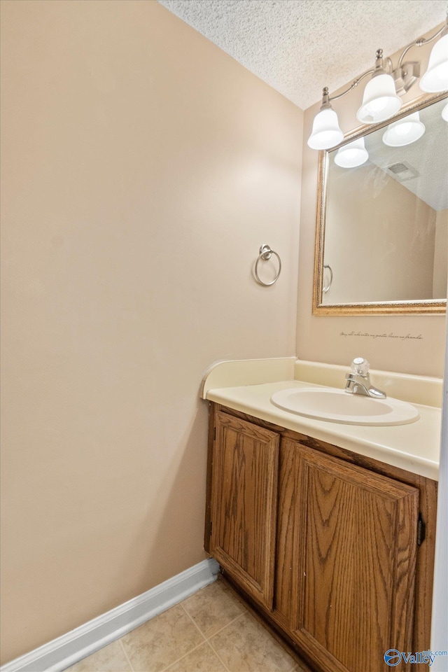 bathroom with a textured ceiling, visible vents, baseboards, vanity, and tile patterned floors