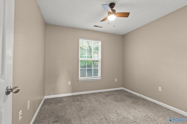 empty room featuring carpet floors, visible vents, a textured ceiling, and baseboards