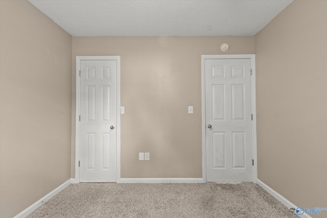 unfurnished bedroom featuring carpet flooring, a textured ceiling, and baseboards