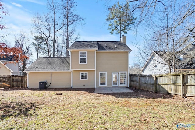 rear view of property featuring central AC unit, a lawn, a fenced backyard, a chimney, and a patio area