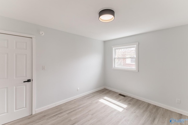 spare room featuring baseboards, light wood-style flooring, and visible vents