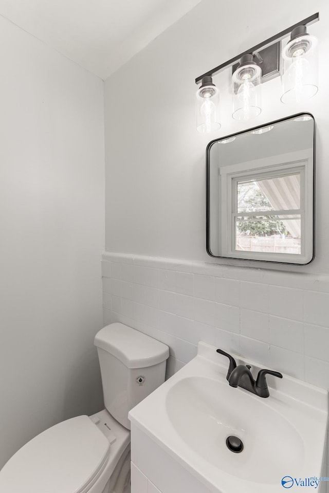 bathroom featuring toilet, a sink, and tile walls