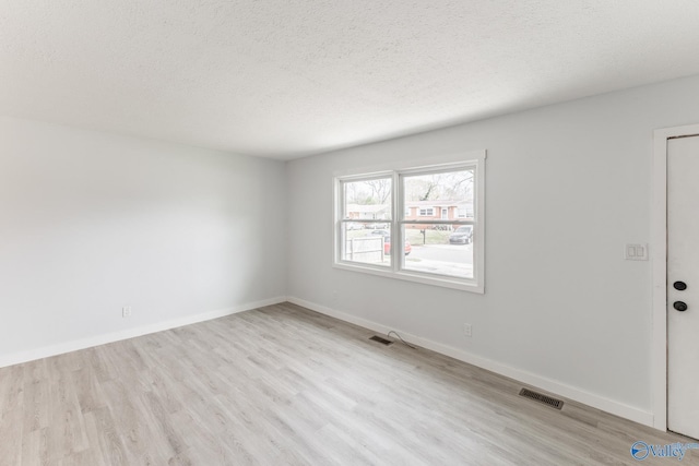 unfurnished room featuring wood finished floors, visible vents, and a textured ceiling