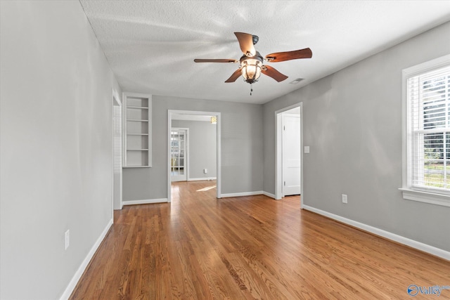 unfurnished room with hardwood / wood-style floors, ceiling fan, and a textured ceiling