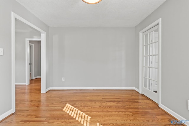 unfurnished room with wood-type flooring and a textured ceiling