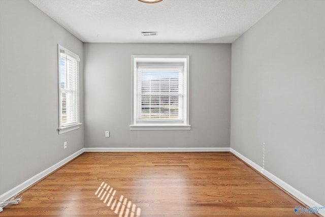 spare room with a textured ceiling and light hardwood / wood-style floors