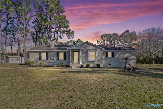 single story home featuring a yard and a storage unit