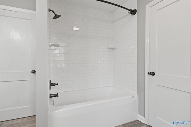 bathroom with hardwood / wood-style floors and tiled shower / bath