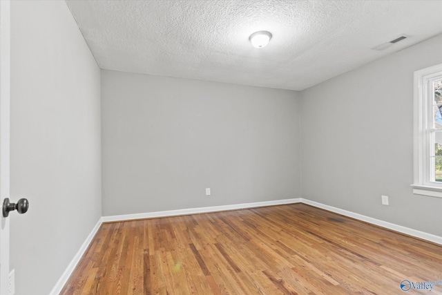 unfurnished room with wood-type flooring and a textured ceiling