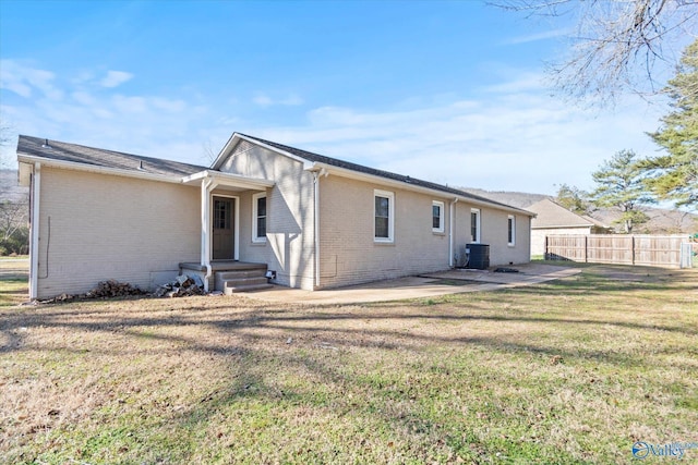 rear view of house featuring a lawn, cooling unit, and a patio